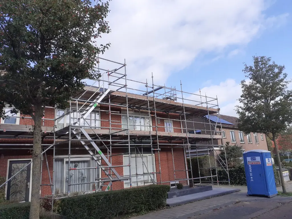 Metselaars aan het werk op een metselsteiger bij nieuwbouw