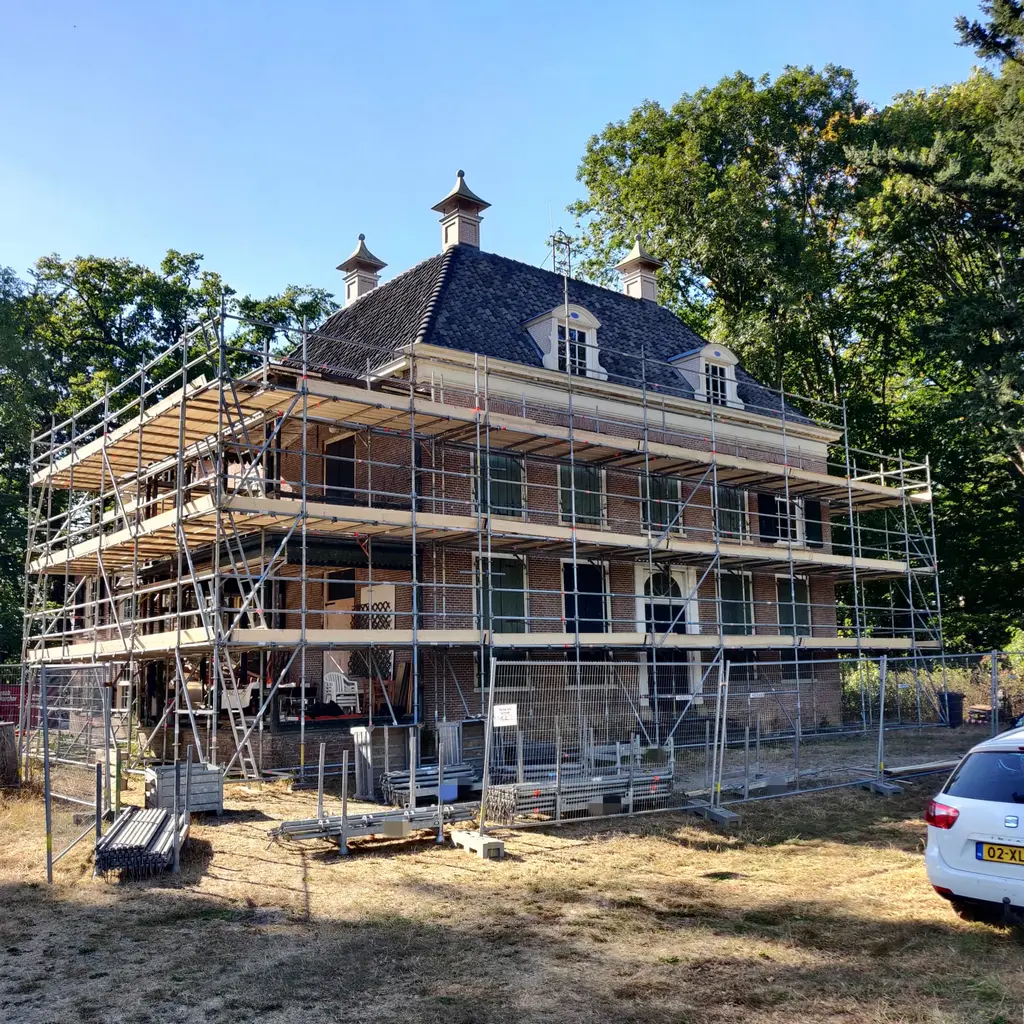 Renovatiesteiger met weerbescherming rond een monumentaal pand